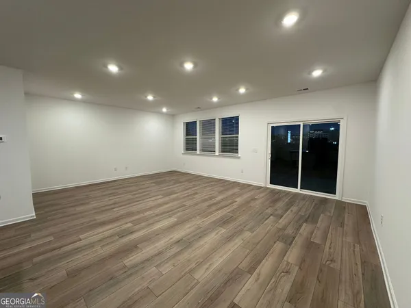 a large kitchen with kitchen island a stove a sink dishwasher a refrigerator and white cabinets with wooden floor