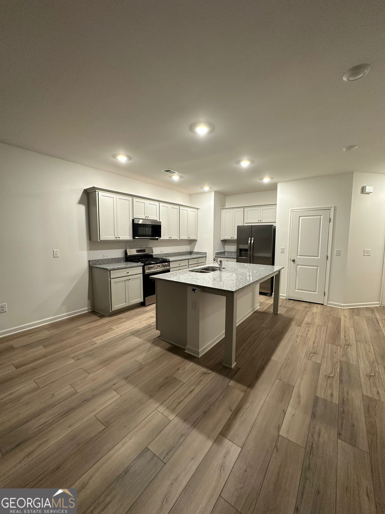 4281 Marsha Street Doraville, GA 30360 - Photo 9 of 38 a large kitchen with kitchen island a stove a sink dishwasher a refrigerator and white cabinets with wooden floor