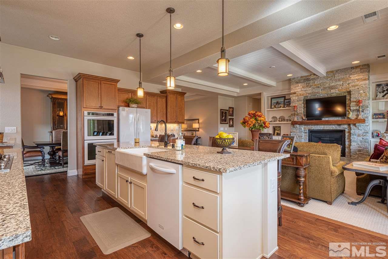 2060 Blue Boy Lane Reno, NV 89521 - Photo 8 of 25 a large kitchen with stainless steel appliances kitchen island granite countertop a table chairs and a wooden floor
