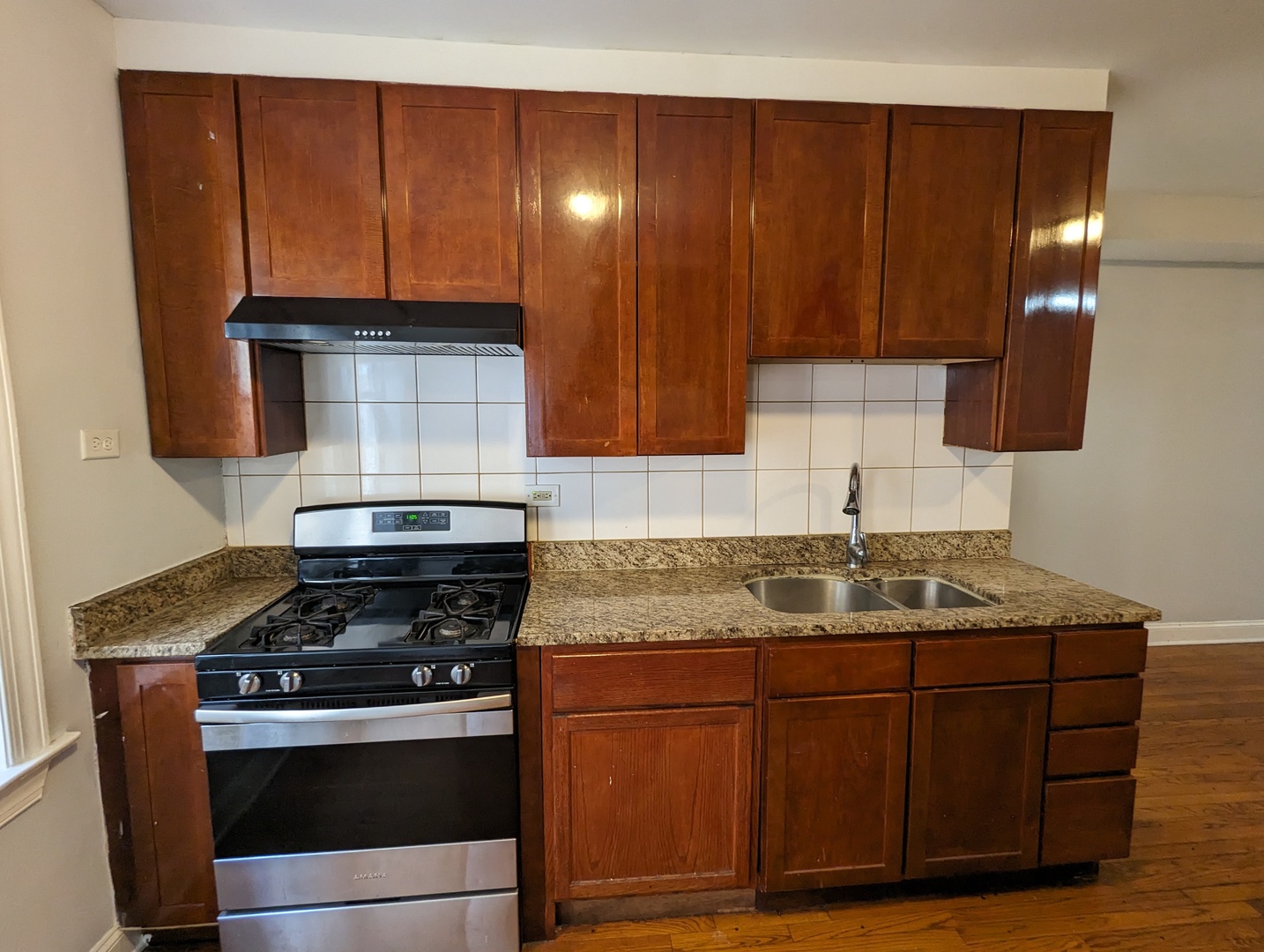 5029 North Harding Avenue, Unit 1W Chicago, IL 60625 - Photo 11 of 18 a kitchen with granite countertop wood cabinets and stainless steel appliances