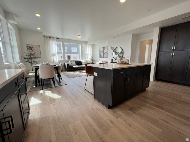 718 West Blue Magic Lane, Unit S201 Midvale, UT 84047 - Photo 17 of 18 Kitchen featuring dark cabinets, open floor plan, a kitchen bar, light wood finished floors, and recessed lighting