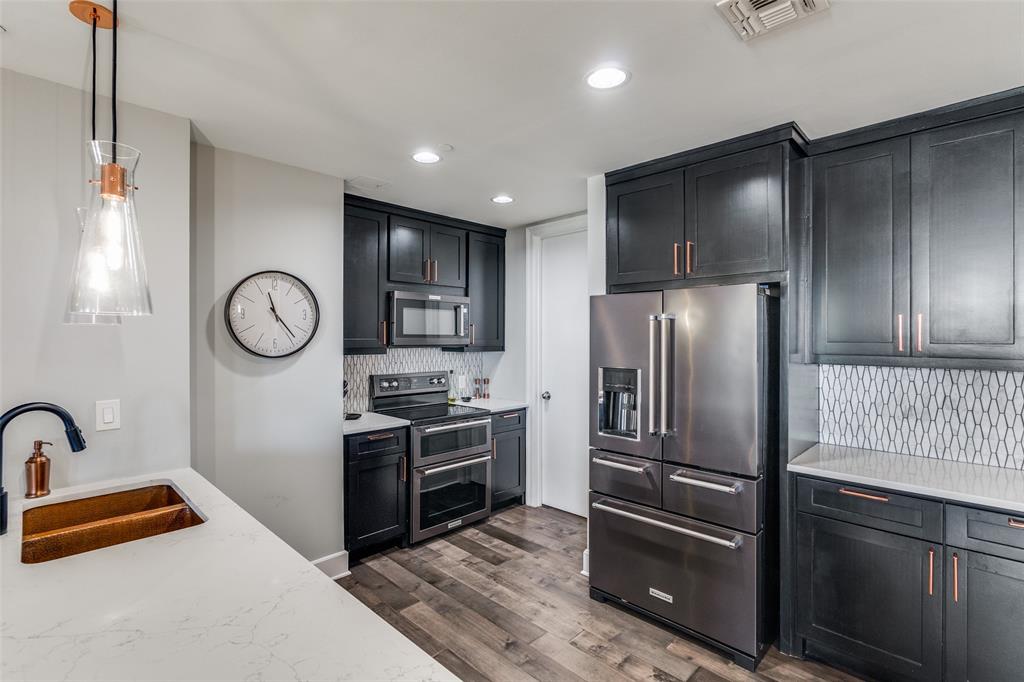 1505 Elm Street, Unit 1504 Dallas, TX 75201 - Photo 7 of 33 Kitchen featuring appliances with stainless steel finishes, decorative backsplash, pendant lighting, light stone counters, and dark wood finished floors