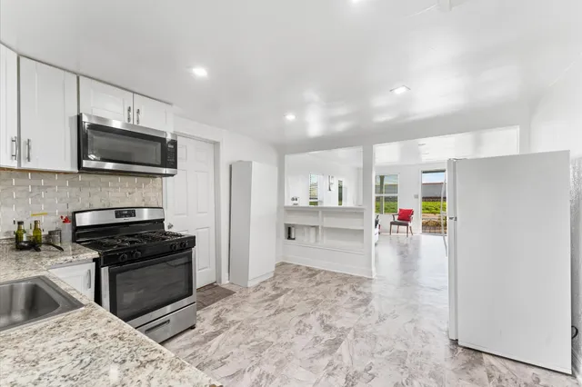 a kitchen with granite countertop a refrigerator and a stove top oven
