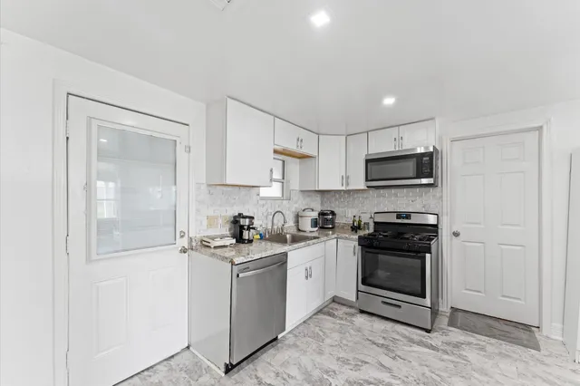 a kitchen with stainless steel appliances granite countertop a stove a sink and a refrigerator