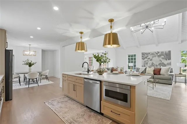 a kitchen with a sink dishwasher a stove and a dining table with wooden floor