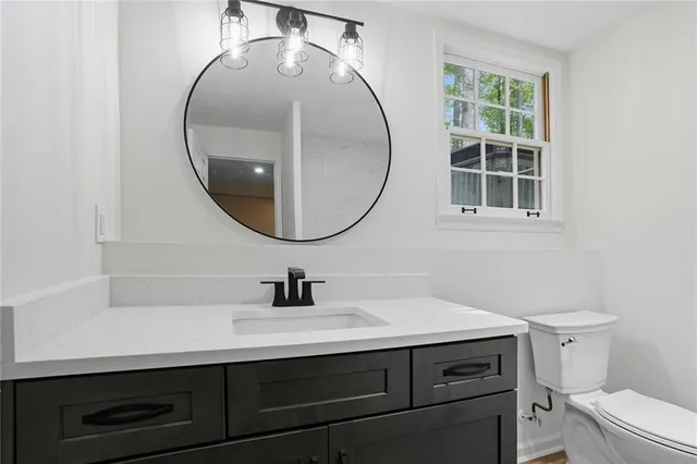 a bathroom with a sink a mirror a toilet and a window