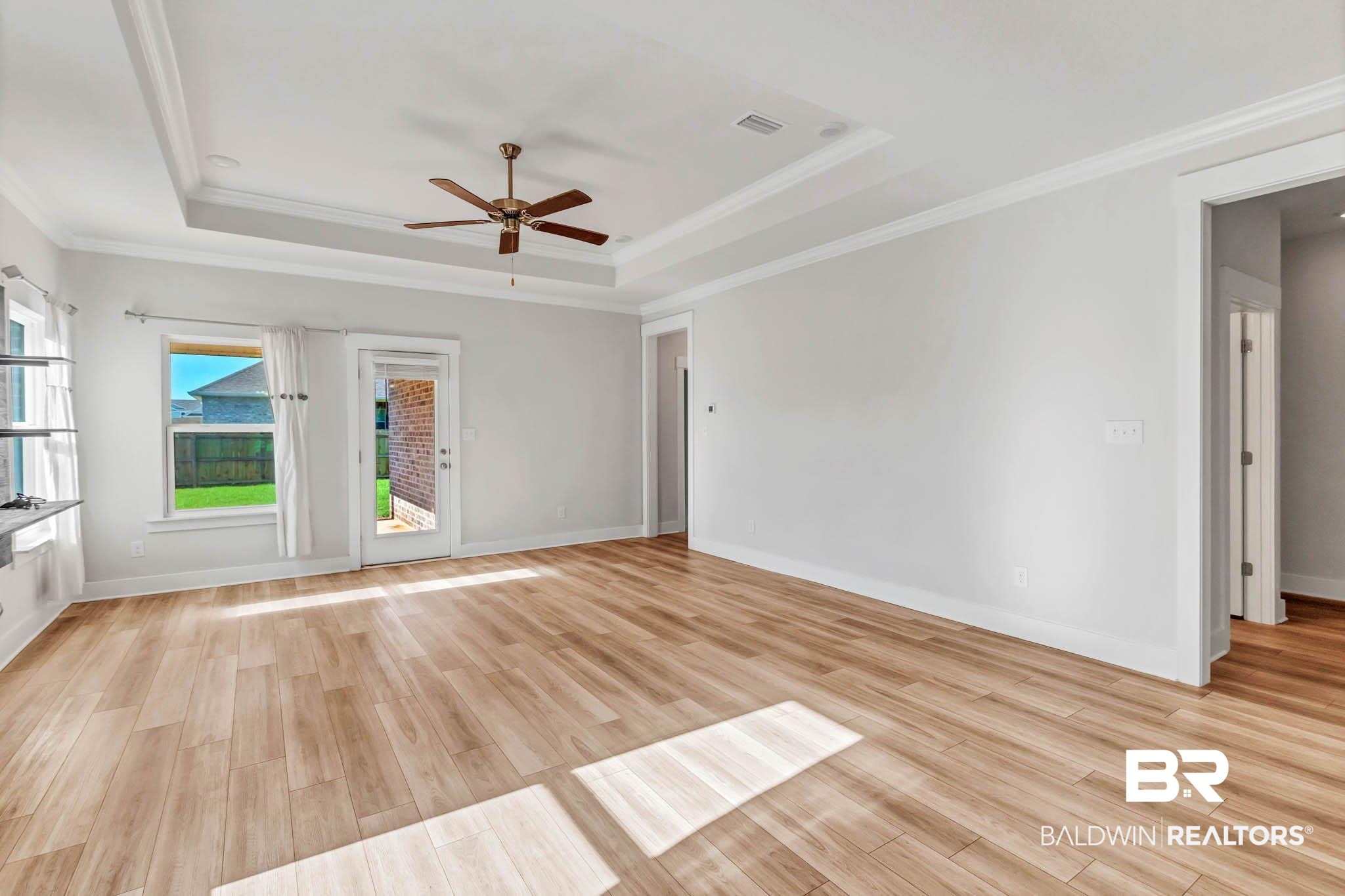 16461 Prado Loop Loxley, AL 36551 - Photo 17 of 78 Empty room with crown molding, a raised ceiling, ceiling fan, and light wood-style floors