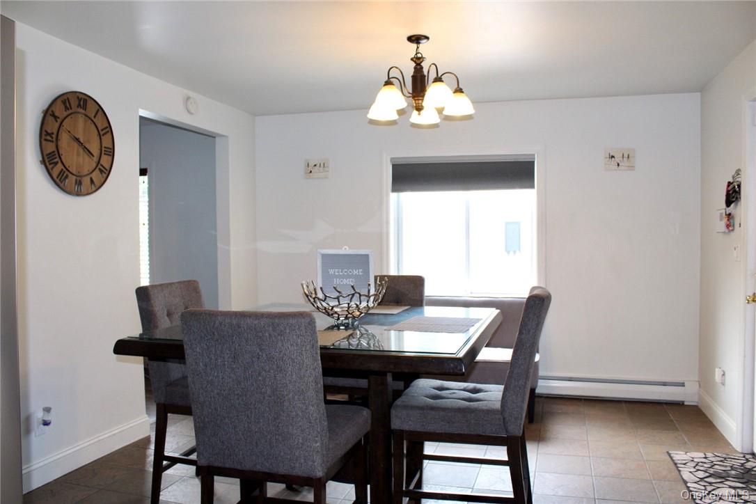 5834 Albany Post Road Cortlandt Manor, NY 10567 - Photo 3 of 14 Dining room with an inviting chandelier, dark tile patterned flooring, and a baseboard heating unit