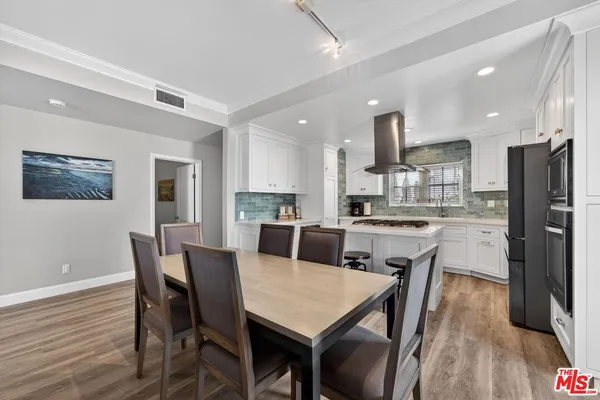 a kitchen with a dining table chairs refrigerator and cabinets