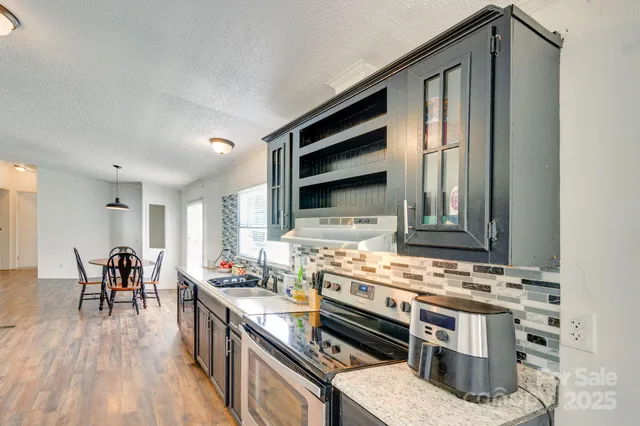 a kitchen with stainless steel appliances a stove a sink cabinets and wooden floor