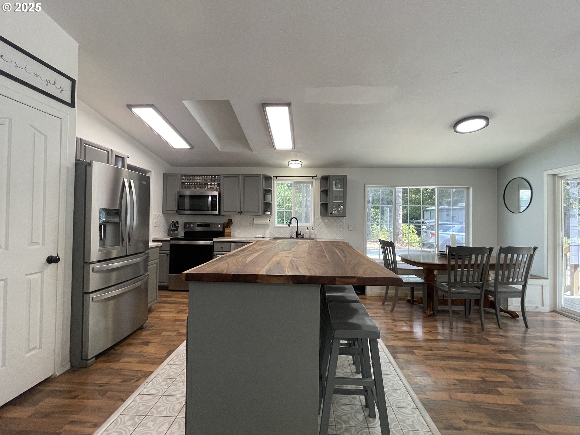 56129 Tom Smith Road Bandon, OR 97411 - Photo 4 of 27 a kitchen with stainless steel appliances kitchen island granite countertop a refrigerator a stove a dining table and chairs with wooden floor