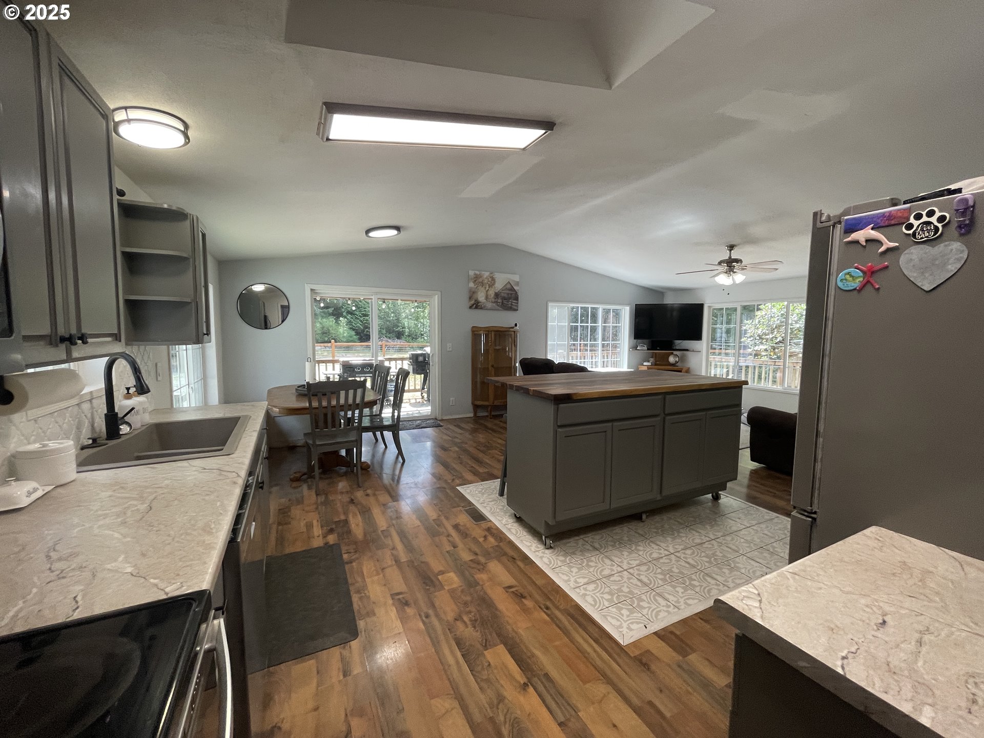 56129 Tom Smith Road Bandon, OR 97411 - Photo 5 of 27 a large kitchen with kitchen island a stove a sink a refrigerator and a dining table with wooden floor