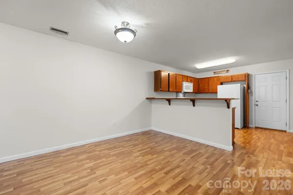 a view of kitchen and empty room with wooden floor