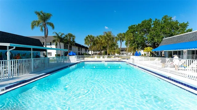 a view of swimming pool with a yard and palm trees