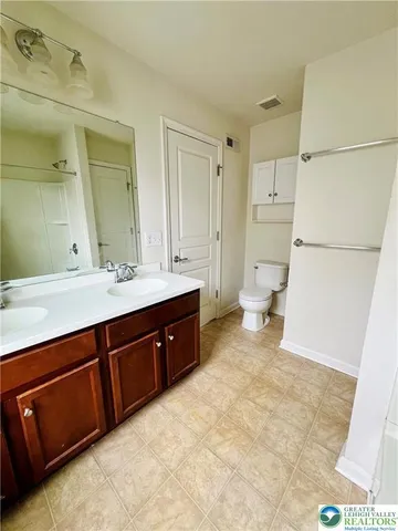 a spacious bathroom with a double vanity sink a mirror and a toilet