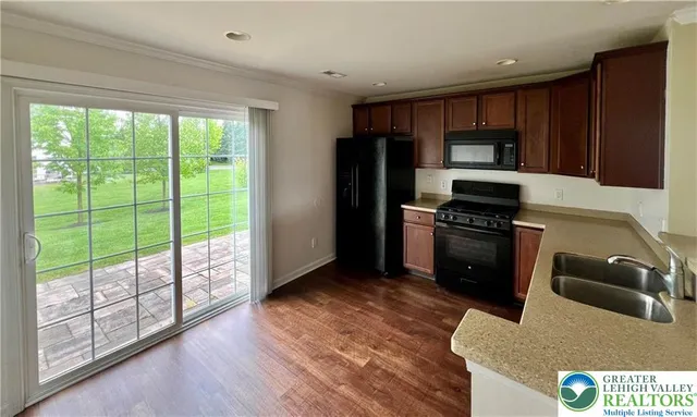 a kitchen with stainless steel appliances granite countertop a refrigerator a stove and a sink with wooden floor