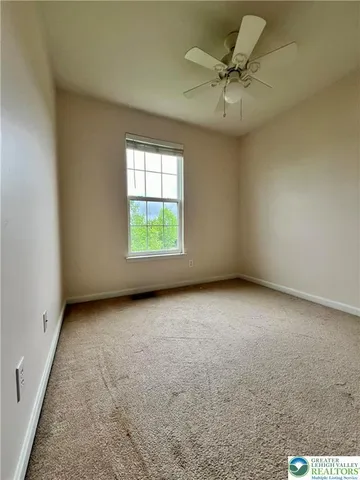 an empty room with a ceiling fan and window