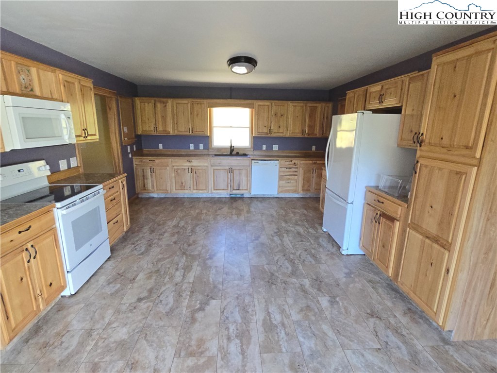 709 Deep Ford Road Lansing, NC 28643 - Photo 8 of 33 a kitchen with granite countertop wooden floors and white stainless steel appliances