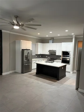 a large kitchen with stainless steel appliances kitchen island granite countertop a refrigerator and a stove top oven