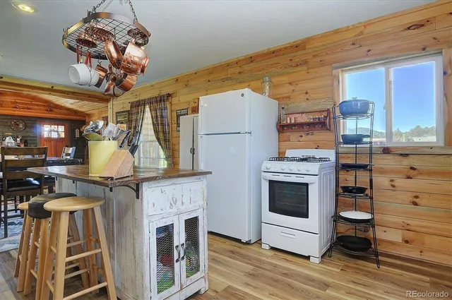 a kitchen with stainless steel appliances granite countertop a stove top oven a dining table and chairs with wooden floor