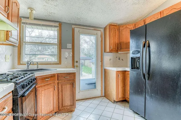 a kitchen with stainless steel appliances granite countertop a refrigerator a stove and a window