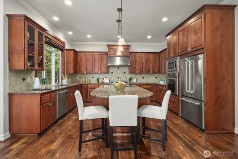 a kitchen with granite countertop wooden floor cabinets dining table and stainless steel appliances