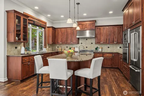 a kitchen with kitchen island granite countertop wooden floors and white stainless steel appliances