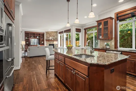 a kitchen with stainless steel appliances granite countertop a sink stove and wooden cabinets