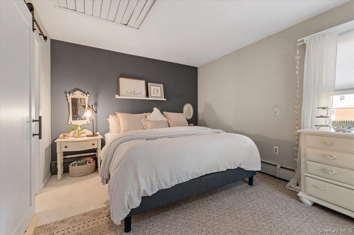 10 Rancher Place Huntington, NY 11743 - Photo 23 of 44 Bedroom featuring a dark accent wall, light neutral wall color, and a window with white blinds