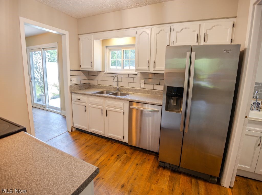 8828 Edgehill Road Mentor, OH 44060 - Photo 4 of 24 Kitchen featuring white cabinets, tasteful backsplash, stainless steel appliances, and light wood-type flooring