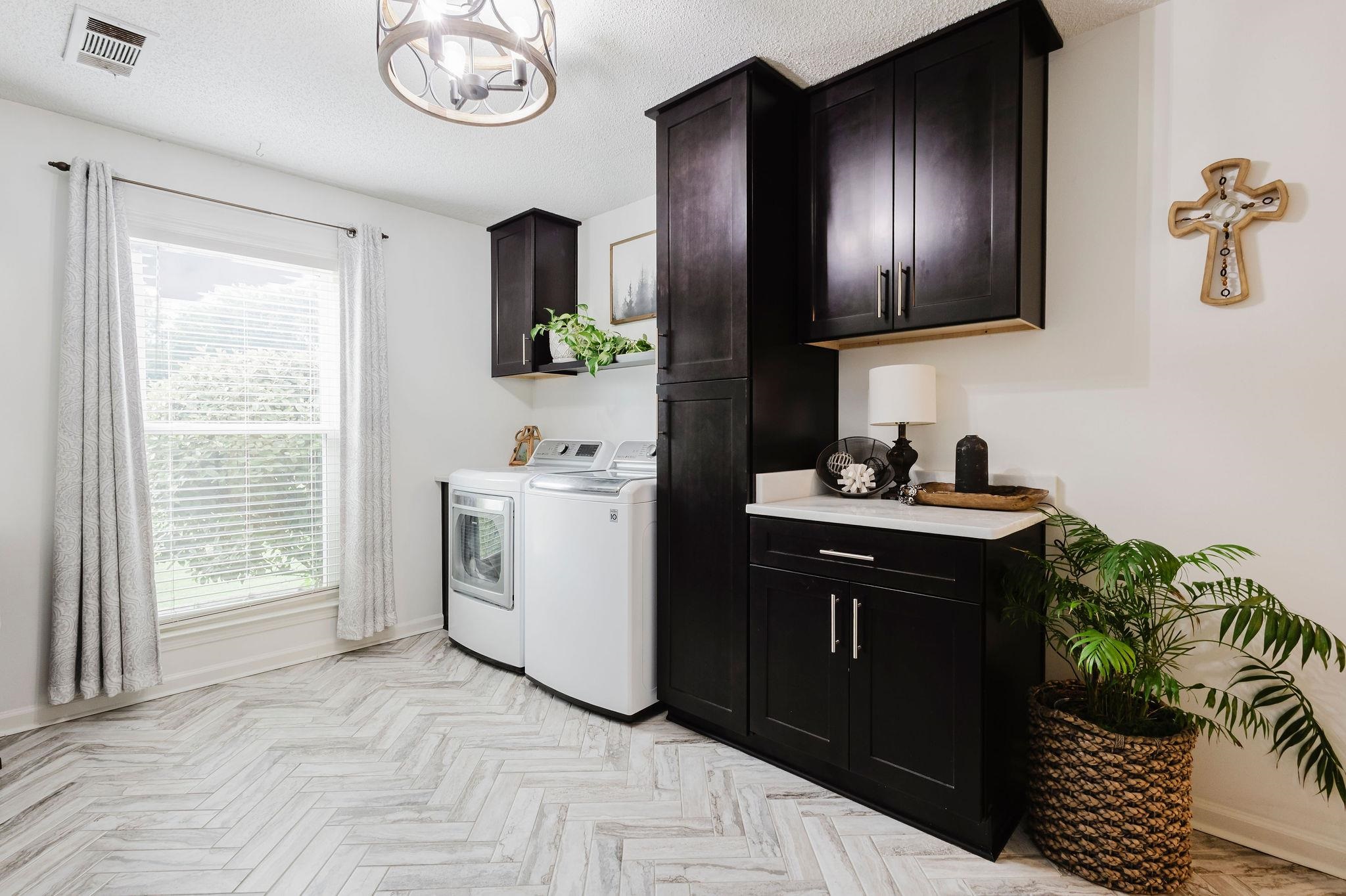 305 Great Falls Road Collierville, TN 38017 - Photo 15 of 23 Laundry room featuring wood-finish herringbone flooring, dark cabinetry with brushed nickel hardware, and a white countertop