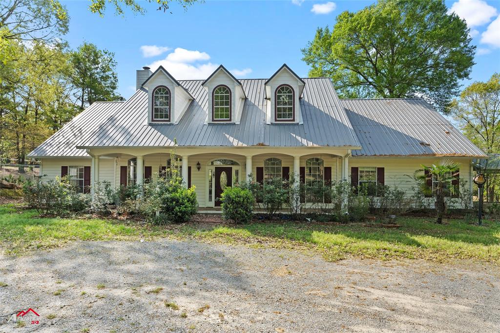 View of front of home featuring a chimney, metal roof, and covered porch