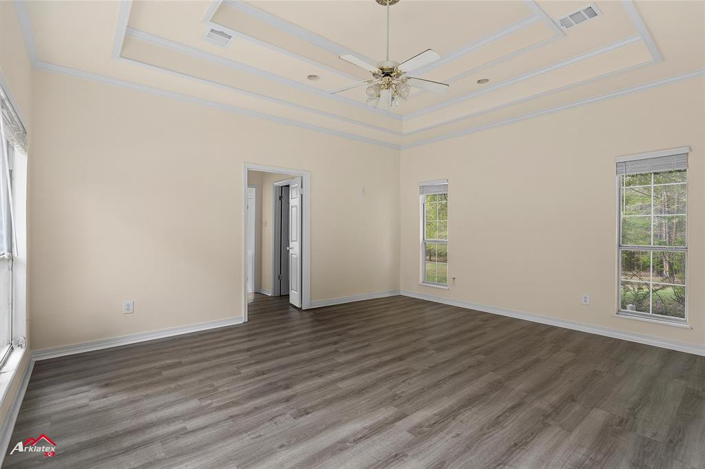 15280 Wynn School Road Hosston, LA 71043 - Photo 13 of 27 Unfurnished room featuring crown molding, a raised ceiling, dark wood finished floors, visible vents, and ceiling fan