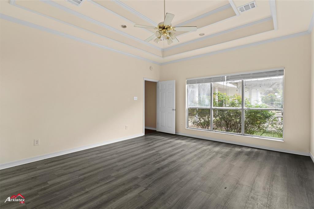 15280 Wynn School Road Hosston, LA 71043 - Photo 14 of 27 Empty room featuring dark wood-style flooring, visible vents, crown molding, a ceiling fan, and a tray ceiling