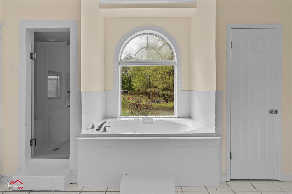 15280 Wynn School Road Hosston, LA 71043 - Photo 15 of 27 Bathroom featuring a bath, tile patterned floors, and a shower stall