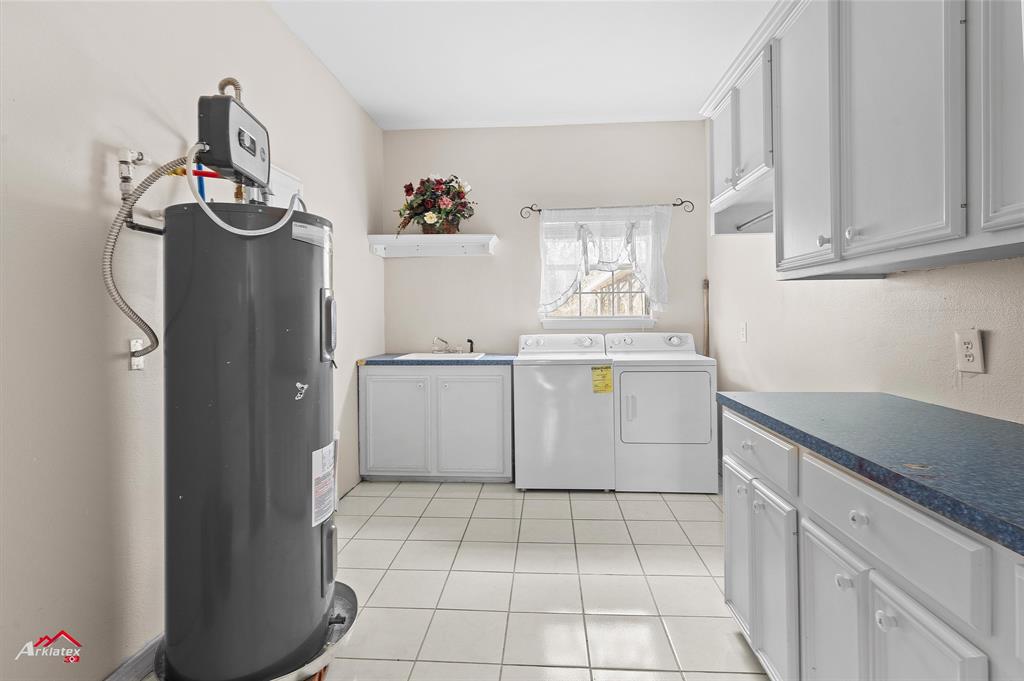 15280 Wynn School Road Hosston, LA 71043 - Photo 17 of 27 Laundry room featuring light tile patterned flooring, a sink, cabinet space, electric water heater, and separate washer and dryer