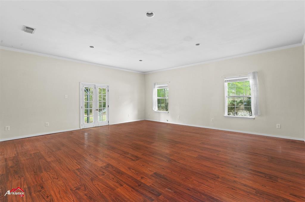 15280 Wynn School Road Hosston, LA 71043 - Photo 18 of 27 Empty room with ornamental molding, visible vents, french doors, and wood finished floors