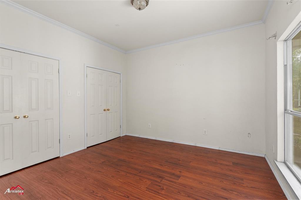 15280 Wynn School Road Hosston, LA 71043 - Photo 19 of 27 Unfurnished bedroom featuring baseboards, multiple closets, wood finished floors, and crown molding