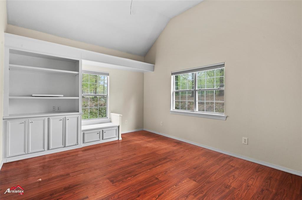 15280 Wynn School Road Hosston, LA 71043 - Photo 20 of 27 Unfurnished room with baseboards, dark wood-style floors, vaulted ceiling, and plenty of natural light