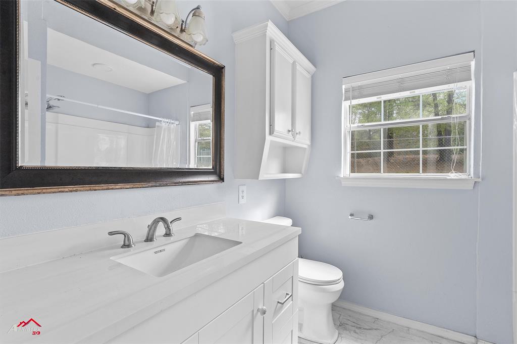 15280 Wynn School Road Hosston, LA 71043 - Photo 21 of 27 Bathroom featuring baseboards, marble finish floor, toilet, vanity, and a shower with curtain