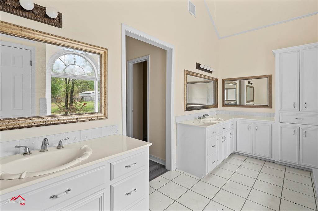 15280 Wynn School Road Hosston, LA 71043 - Photo 22 of 38 a bathroom with a granite countertop sink and mirror with window
