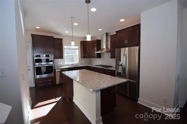 a kitchen with stainless steel appliances granite countertop a refrigerator a sink a stove and a refrigerator with wooden floor