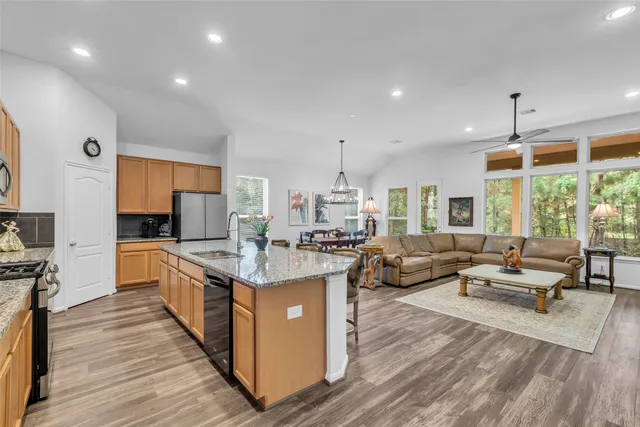 a large kitchen with stainless steel appliances kitchen island granite countertop a large counter top a stove and a sink