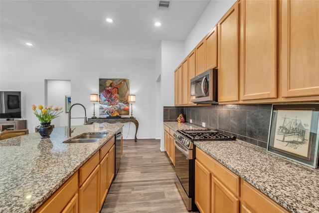 a kitchen with stainless steel appliances granite countertop a stove a sink and a microwave