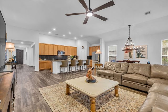 a living room with furniture kitchen view and a chandelier