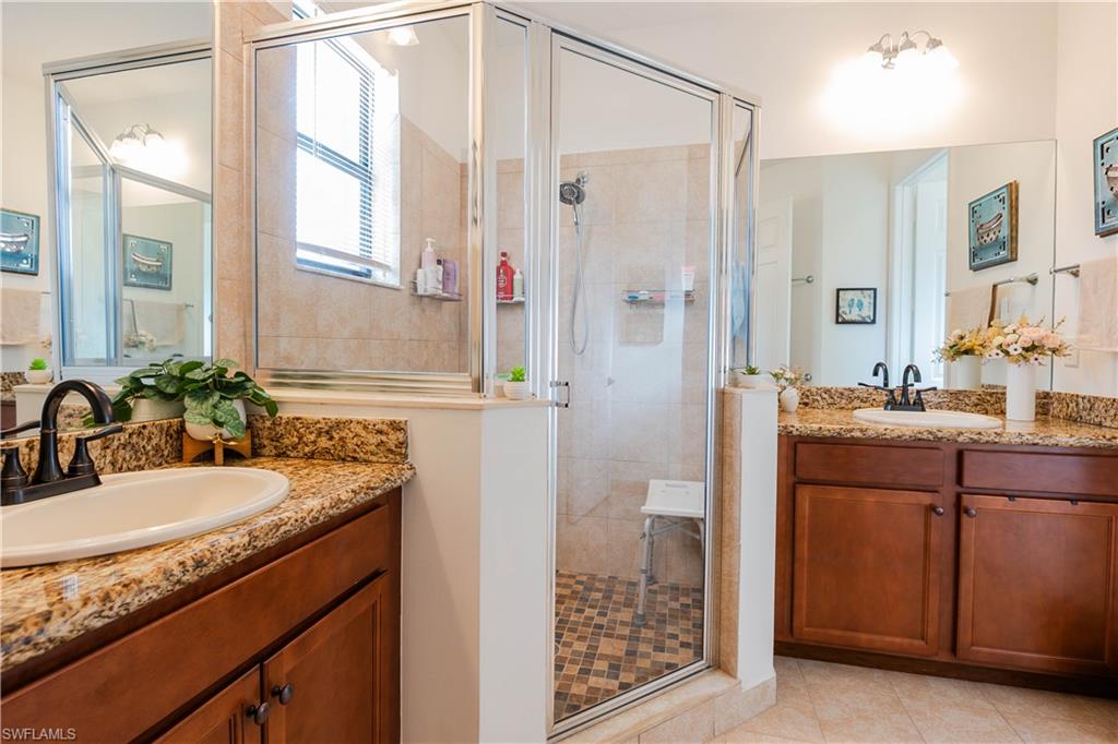5092 Beckton Road Ave Maria, FL 34142 - Photo 25 of 36 a bathroom with a granite countertop sink a mirror and a shower