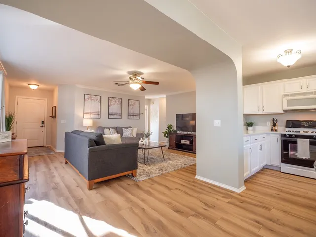 a view of a dining room and livingroom with furniture wooden floor a rug a fireplace and a chandelier