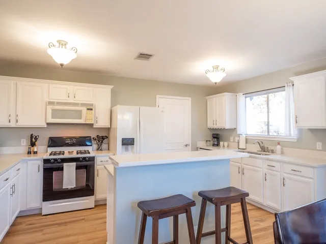 a kitchen with stainless steel appliances a stove a sink dishwasher a microwave oven and a dining table with wooden floor