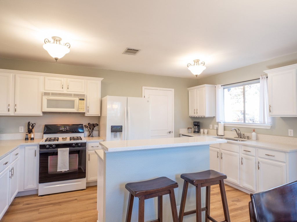 9610 Dalewood Drive Austin, TX 78729 - Photo 9 of 27 a kitchen with stainless steel appliances a stove a sink dishwasher a microwave oven and a dining table with wooden floor