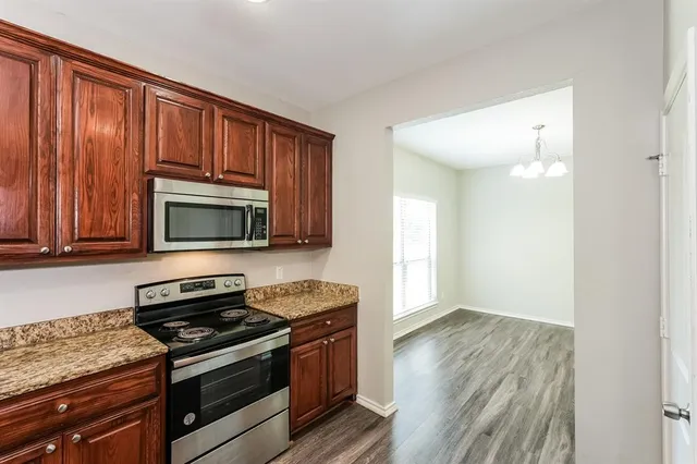 a kitchen with granite countertop wooden cabinets and stainless steel appliances